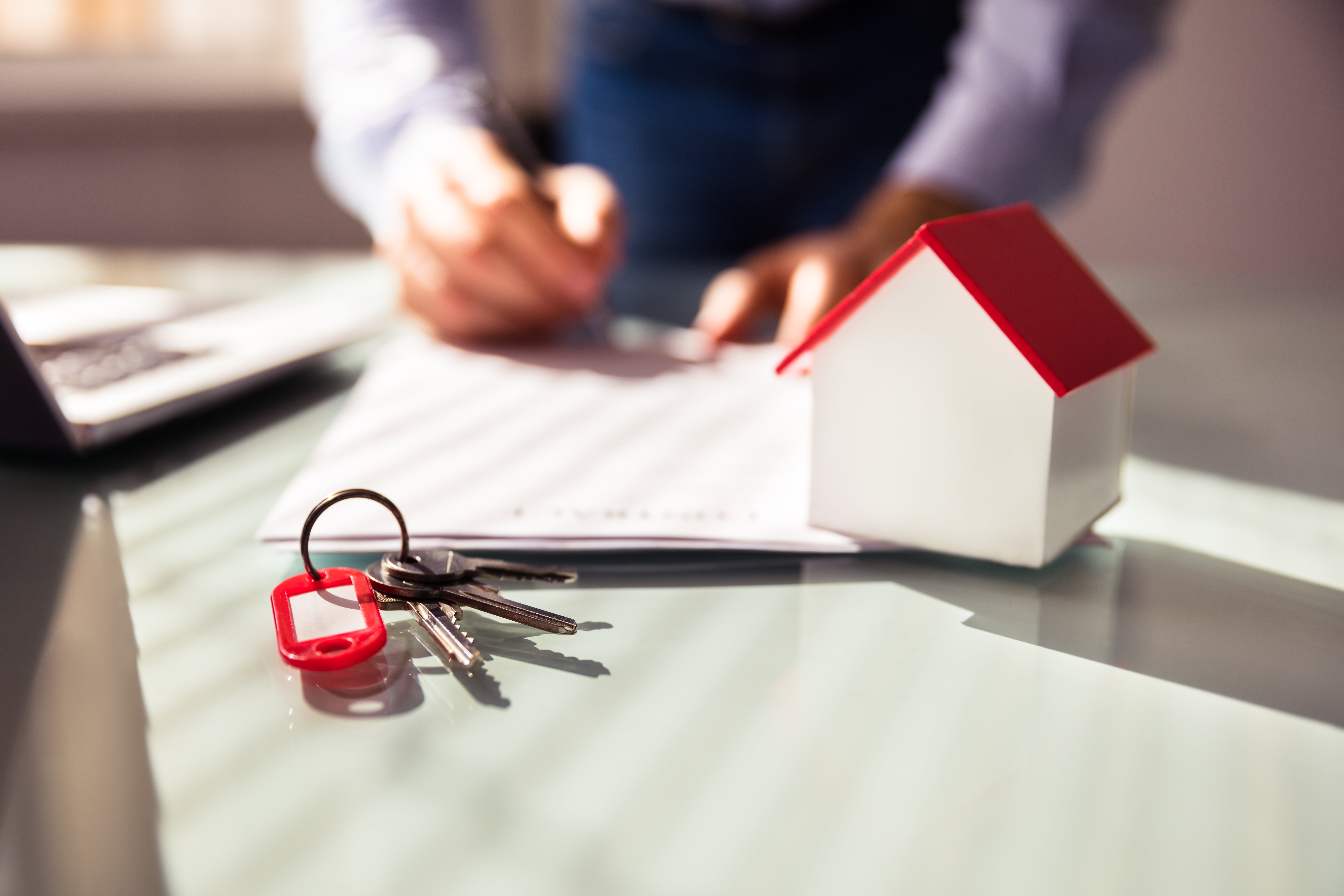 Close-up Of House Model And Key Near Human Hand Signing Contract