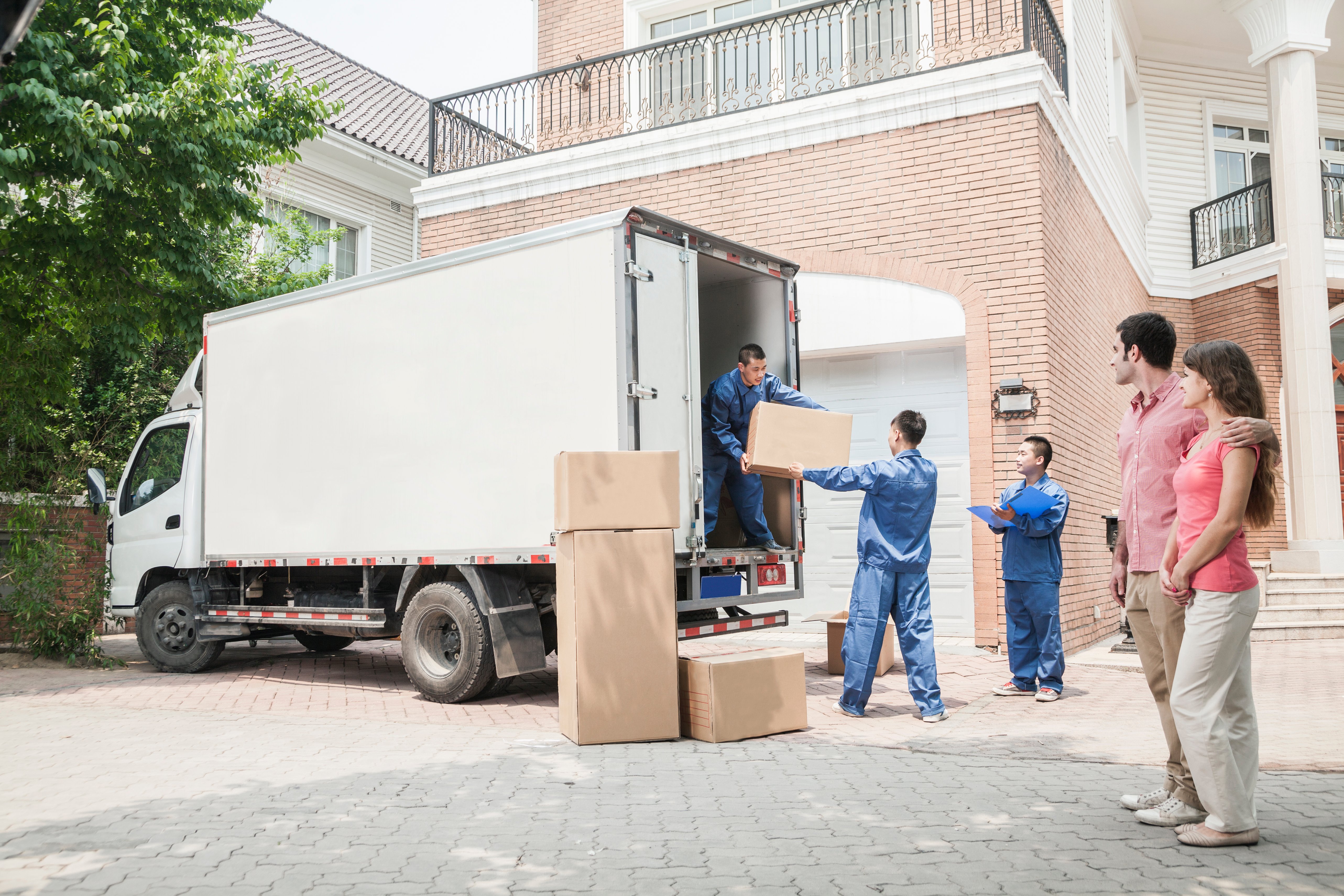 Couple watching movers move boxes from the moving van