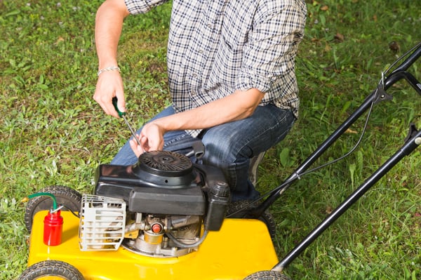 A man using tool on a powered lawn mower