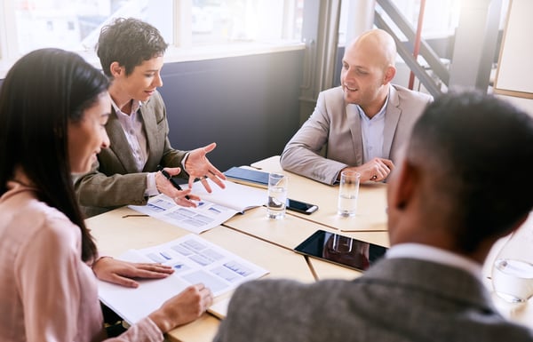 Four people in a business meeting discussing a document