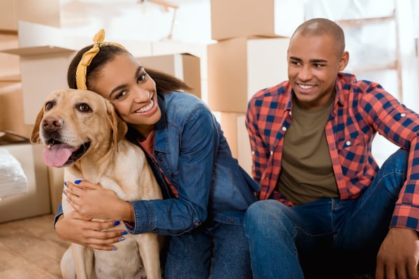 A woman sitting next to a man while hugging a dog