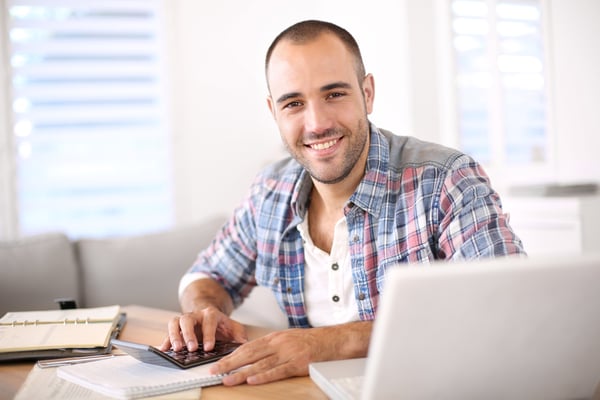 A man using a calculator and laptop