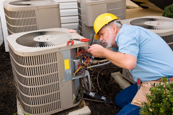 A man with a yellow hard-hat fixes an air conditioner