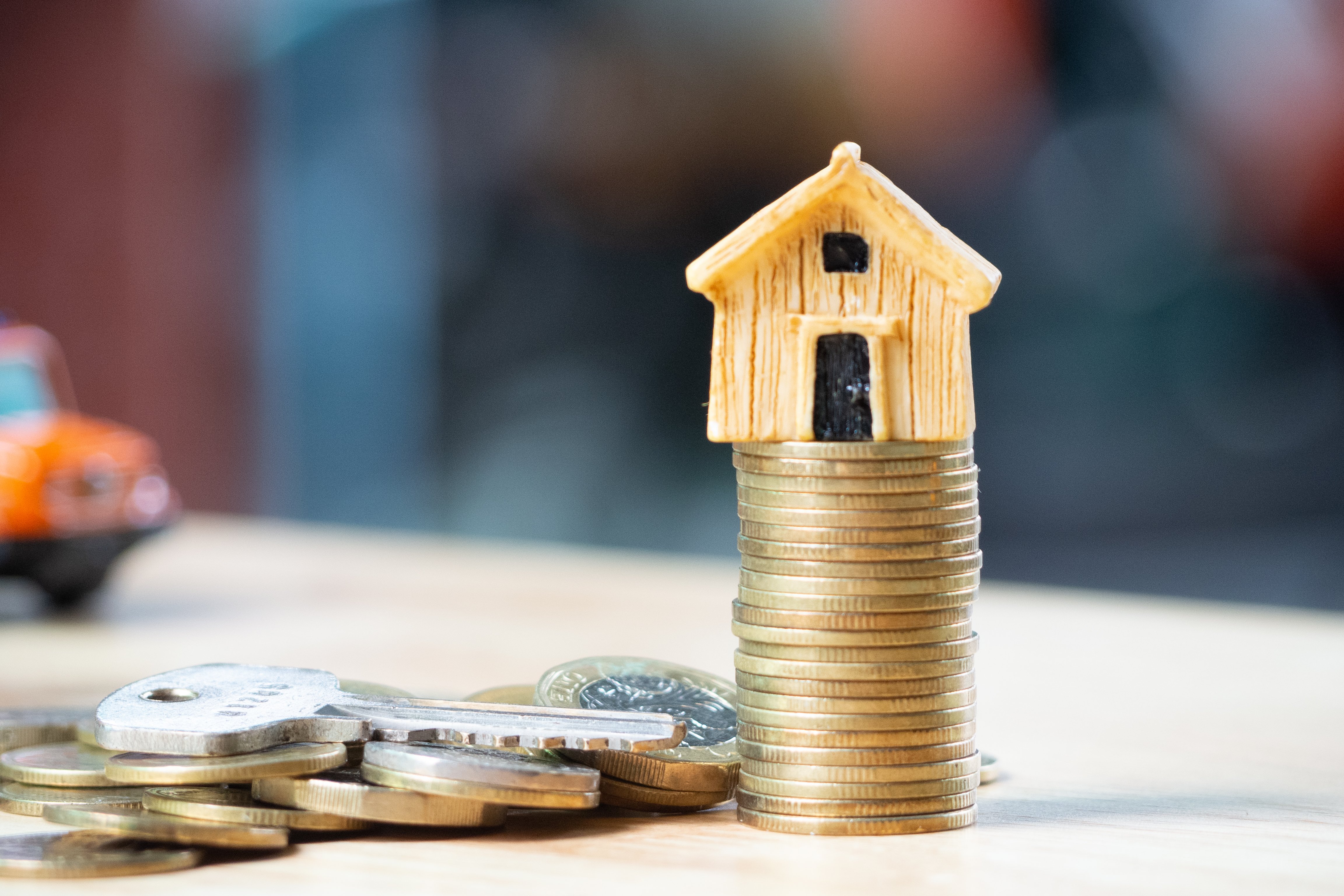 House or Home model on near of coins stack with home key. Concept for loan, property ladder, financial, mortgage, real estate investment, taxes and bonus.